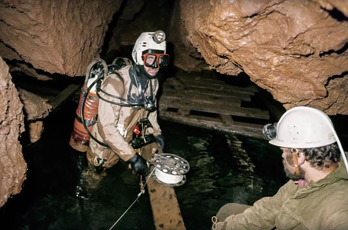 Slovenský kras – Skalistý potok. Potápačský prieskum. 11. 9. 1982. Speleopotápač Jozef Kucharovič. Asistuje mu Jaroslav Košťal. Pred prvým sifónom, drevená plošina od IGHP. © 1982 Gustáv Stibrányi